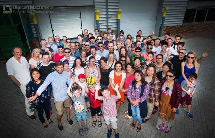 Group photo of diverse team members in a workplace setting, showcasing camaraderie and teamwork, reflecting corporate culture and professional engagement.