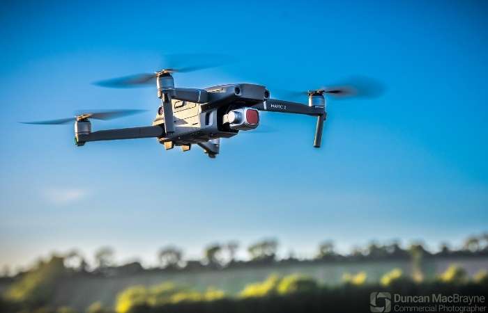 Drone in flight against a clear blue sky, showcasing aerial photography capabilities for commercial and construction projects.