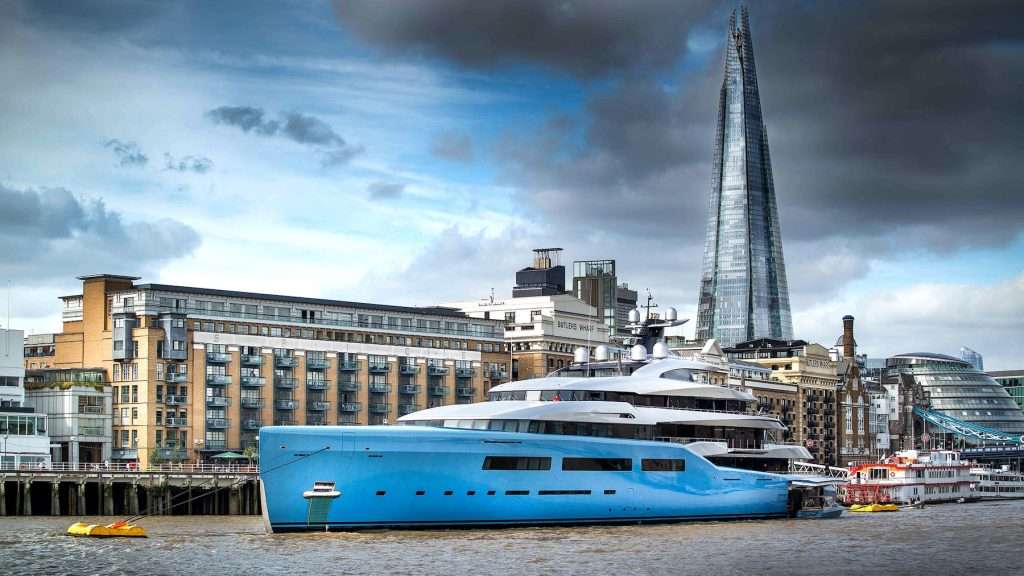 Luxury yacht moored on the River Thames with the Shard skyscraper in the background, showcasing urban architecture and maritime scenery in London.