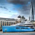 Luxury blue yacht moored by the river with The Shard skyscraper in the background, representing marine photography in Duncan MacBrayne's portfolio.