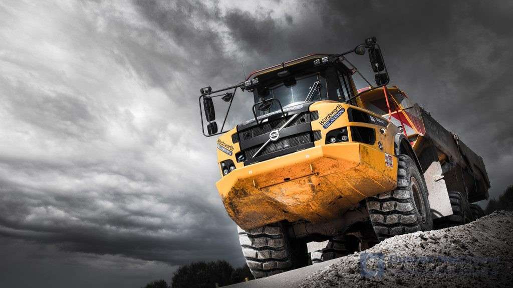 Heavy-duty Volvo dumper truck on construction site with dramatic cloudy sky, showcasing industrial photography expertise by Duncan MacBrayne, commercial photographer in Reading, Berkshire.