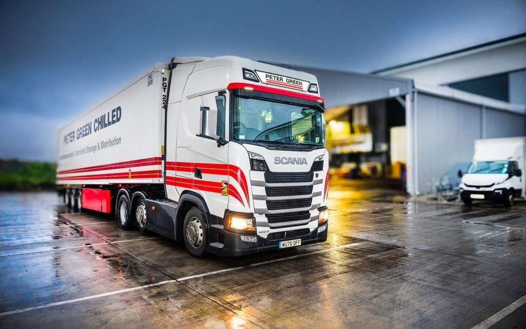 Scania truck with "Peter Green Chilled" branding, parked in an industrial setting, showcasing commercial transportation and logistics services.