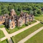 Aerial view of a luxurious property surrounded by greenery, showcasing intricate architectural details and manicured gardens, representing high-end real estate photography in Berkshire.