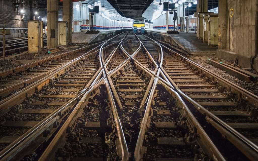 Railway tracks converging in an underground station, showcasing a train at rest, highlighting Duncan MacBrayne's expertise in railway construction and industrial photography.