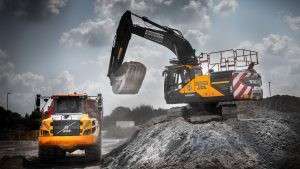 Excavator and dumper truck operating on construction site, showcasing industrial machinery in action.