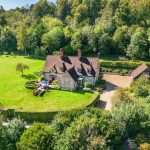 Aerial view of a luxury property surrounded by lush greenery and landscaped gardens, showcasing the spacious grounds and elegant architecture, relevant to Duncan MacBrayne's commercial property photography services in Reading and Berkshire.