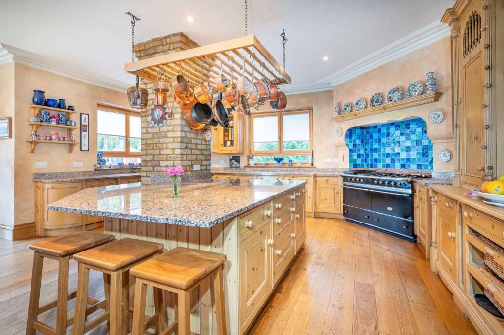 Luxury kitchen with granite countertop, wooden cabinets, hanging pots, and blue tiled backsplash, showcasing professional property photography by Duncan MacBrayne.