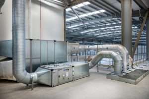 Industrial ventilation system with ductwork and air handling unit in a spacious commercial facility, showcasing Duncan MacBrayne's industrial photography expertise.