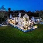 Luxury property exterior at dusk, showcasing illuminated features and landscaped garden, highlighting Duncan MacBrayne's commercial photography services in Berkshire.