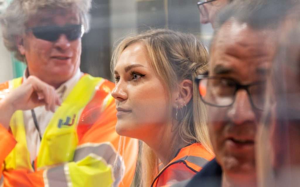 Group of professionals in high-visibility clothing engaged in discussion, highlighting industrial and corporate photography themes relevant to Duncan MacBrayne's portfolio.