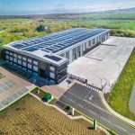 Aerial view of a modern industrial building with solar panels, surrounded by landscaped grounds and a paved parking area, showcasing commercial property photography by Duncan MacBrayne in Reading, Berkshire.
