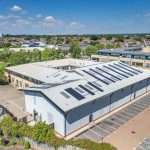 Aerial view of a modern industrial building with solar panels on the roof, located in Reading, Berkshire, showcasing commercial property photography by Duncan MacBrayne.
