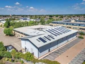 Aerial view of a commercial building with solar panels in Reading, Berkshire, showcasing industrial architecture and surrounding landscape.