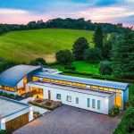 Modern luxury property with landscaped garden, rolling green hills in background, and contemporary architectural design, showcasing Duncan MacBrayne's professional photography expertise in commercial and property photography.