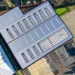 Aerial view of a modern industrial building with multiple parking spaces and a sleek grey roof, showcasing Duncan MacBrayne's commercial photography expertise.