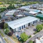 Aerial view of a modern industrial building surrounded by commercial properties and greenery, showcasing the industrial photography services offered by Duncan MacBrayne in Reading, Berkshire.
