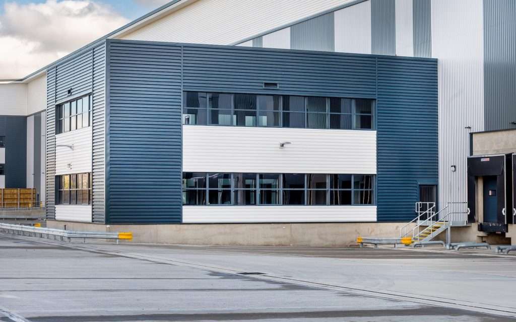 Modern industrial building exterior with blue and white cladding, large windows, and loading dock area, representing commercial property photography by Duncan MacBrayne in Reading, Berkshire.