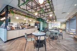 Modern café interior with stylish seating, greenery, and a coffee counter, showcasing Duncan MacBrayne's commercial photography expertise in capturing dynamic spaces.