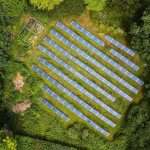 Aerial view of solar panels arranged in a geometric pattern within a green landscape, showcasing renewable energy solutions relevant to commercial and industrial photography projects.