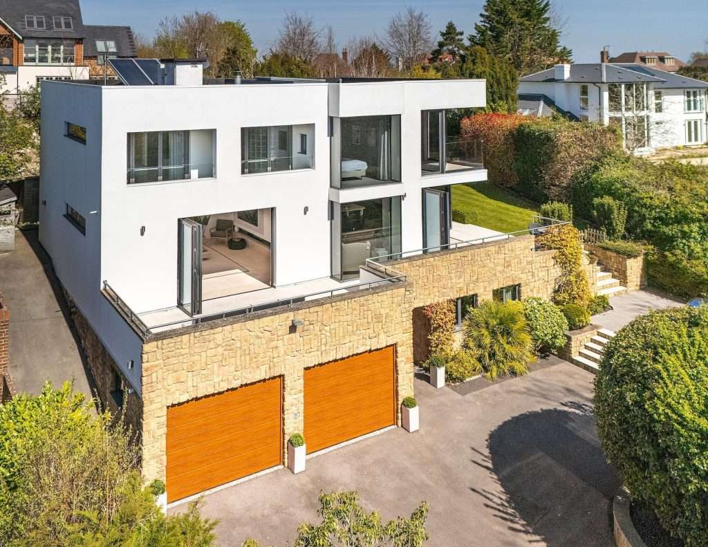 Modern luxury property with large windows, stone garage, and landscaped garden in Reading, Berkshire.