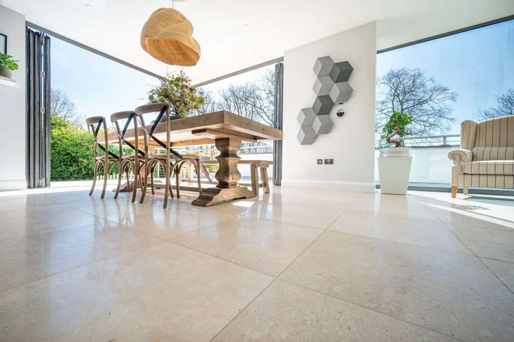 Modern dining area featuring a wooden table with six chairs, large windows providing natural light, decorative hexagonal wall art, and a potted plant, showcasing luxury property interior design.