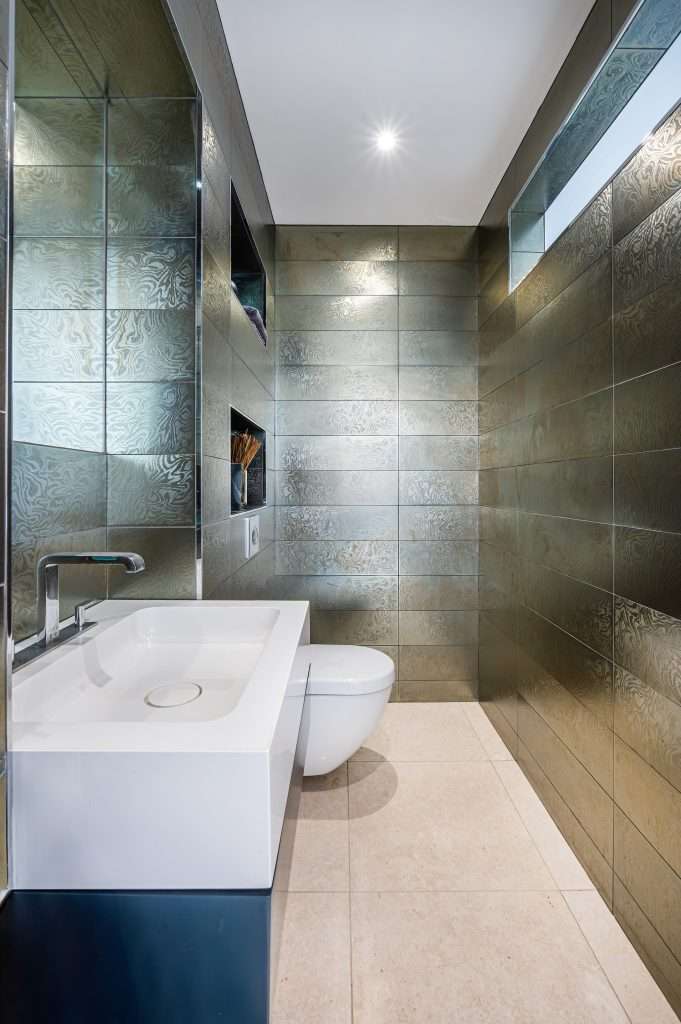 Modern bathroom interior featuring sleek white sink and toilet, with metallic textured walls and minimalist design elements, showcasing luxury property aesthetics.