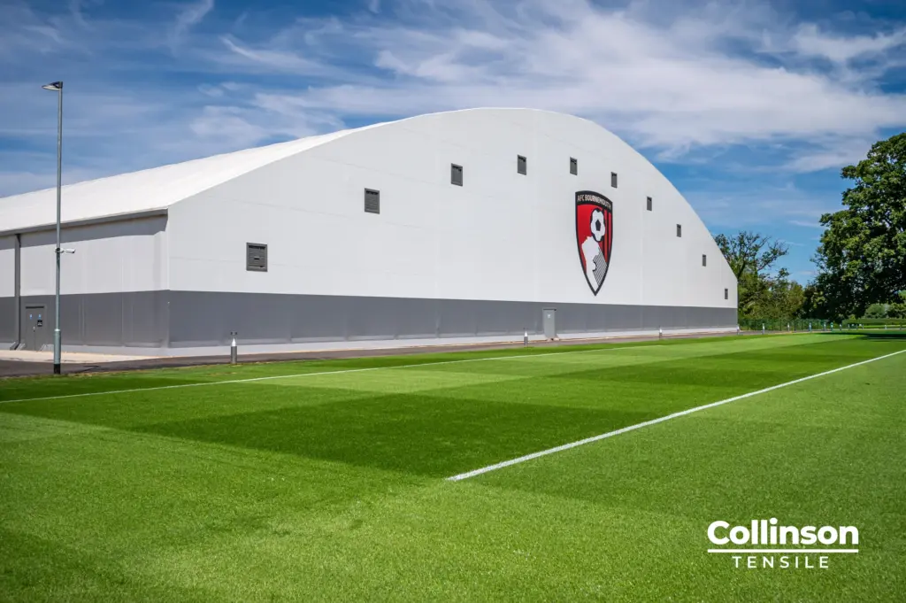 Collinson Tensile AFC Bournemouth Training Facility Dorset 007 Architectural photograph of the AFC Bournemouth indoor training facility exterior and pitch under blue sky